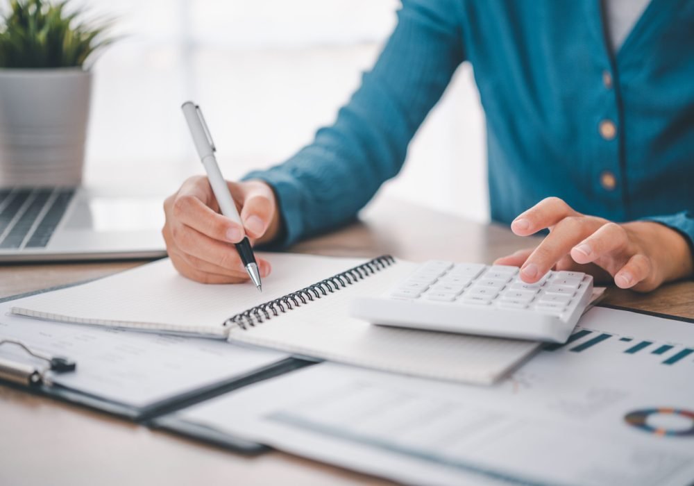 close up The business person is sitting on a calculator with a graph in the office of finance accounting concept