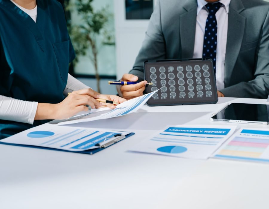 Doctors and consultant discussing brain scan and lab reports in a modern clinic. Healthtech, diagnostics, teamwork, and patient care concept