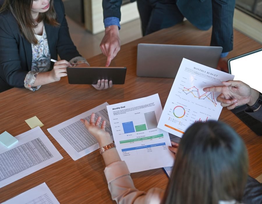 Executive businesspeople brainstorming and analyzing financial reports together in meeting room.