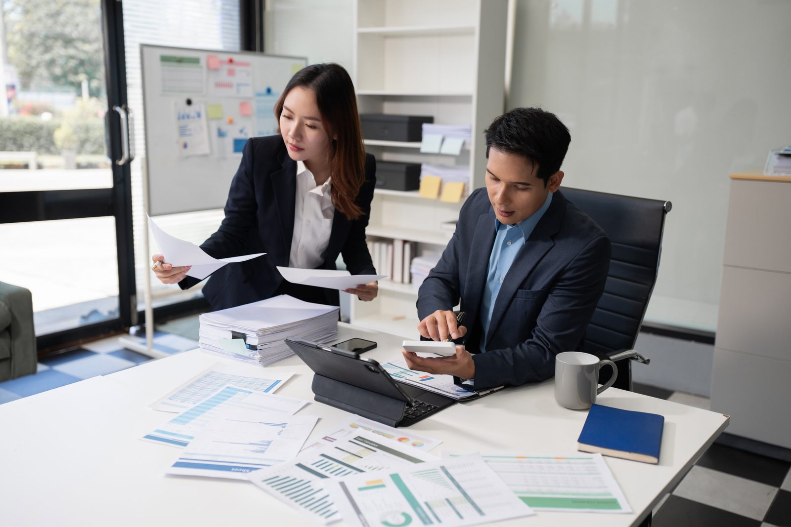 Business documents, data analysis, and teamwork in modern office Business team analyzing documents, graphs, and data with a laptop, tablet, and smartphone. Collaboration, strategy, and success in a modern office.